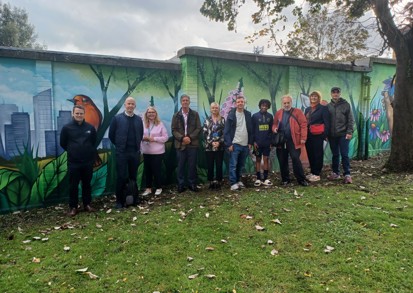 Residents stand beside a community wall mural. 