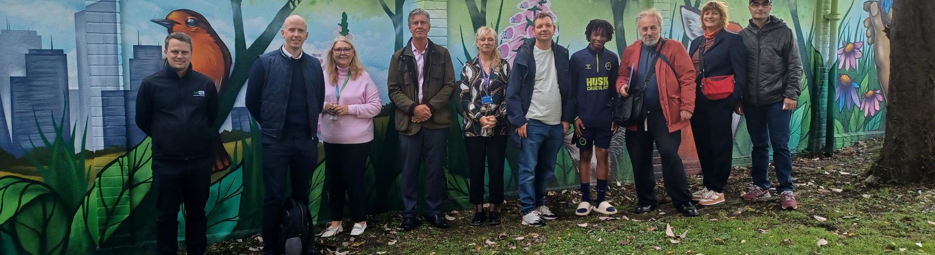 Residents stand beside a community wall mural.