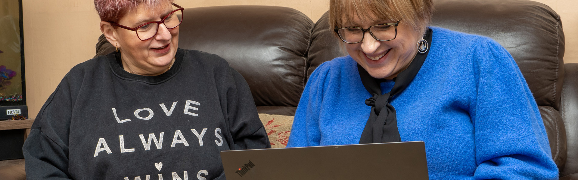 A smiling resident in their home seated with a housing officer.