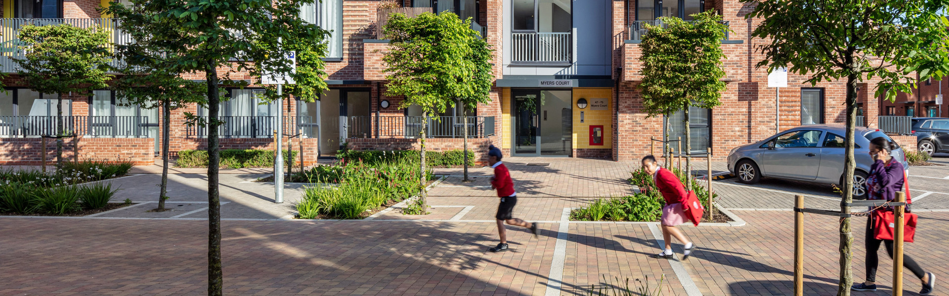 Kids running in front of a housing building