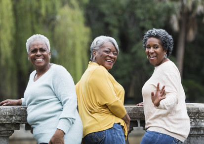 Three middle aged ladies laughing together in a park.